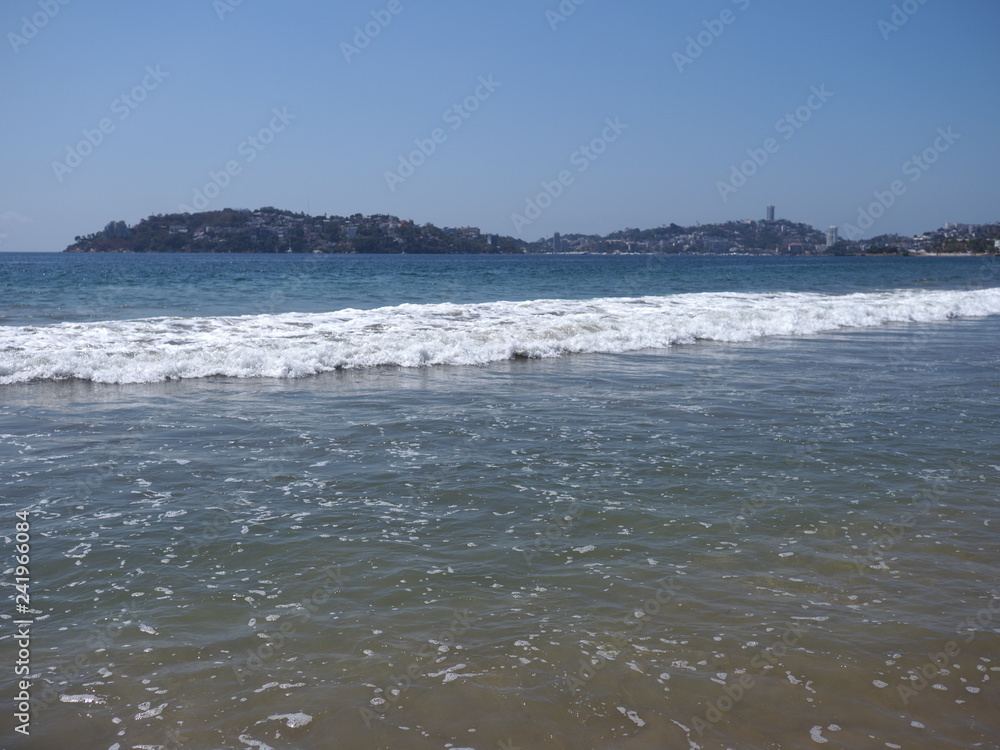 Scenery of calm beach at bay of ACAPULCO city in Mexico and white waves of Pacific Ocean landscape