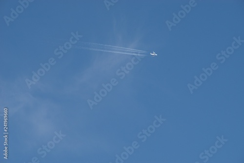 Plane flying on a blue sky, condensation line.
