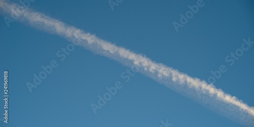 Plane flying on a blue sky, condensation line. © venars.original
