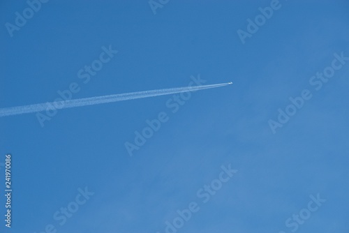 Plane flying on a blue sky  condensation line.