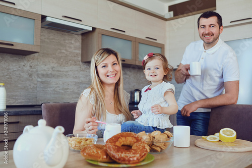 A happy family in the kitchen while sitting at a table.
