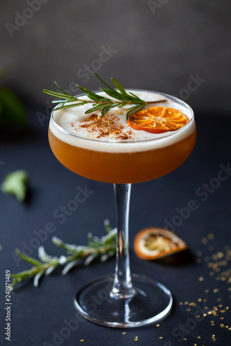 Christmas cocktail of amaretto sour with dehydrated clementine and rosemary