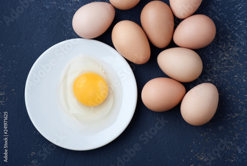 Raw egg guinea fowl in a white plate on a blue background