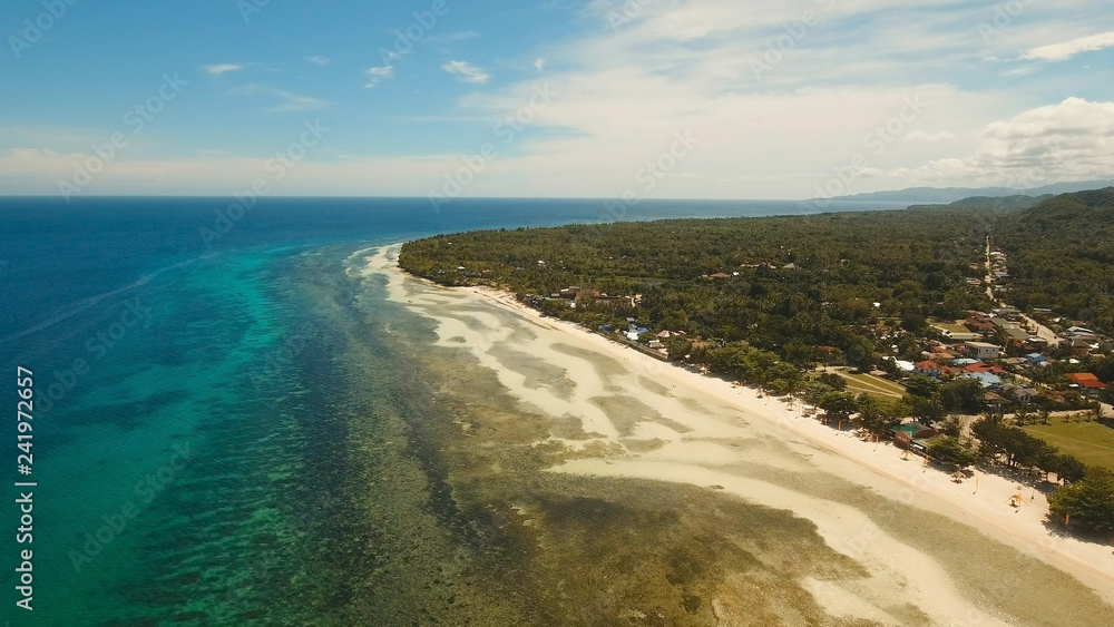 Aerial view of tropical beach on island Bohol, Anda area, Philippines. Beautiful tropical island with sand beach, palm trees. Tropical landscape: beach with palm trees. Seascape: Ocean, sky, sea