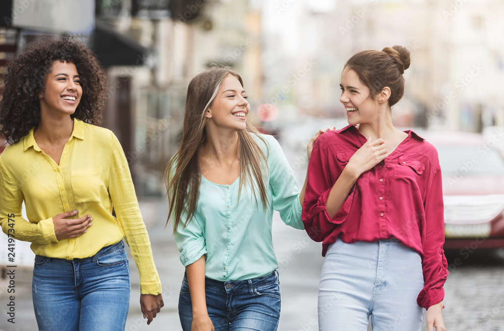 Three happy women walking in the city