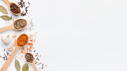 Various spices and herbs in spoons on white background