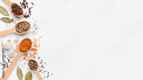 Various spices and herbs in spoons on white background