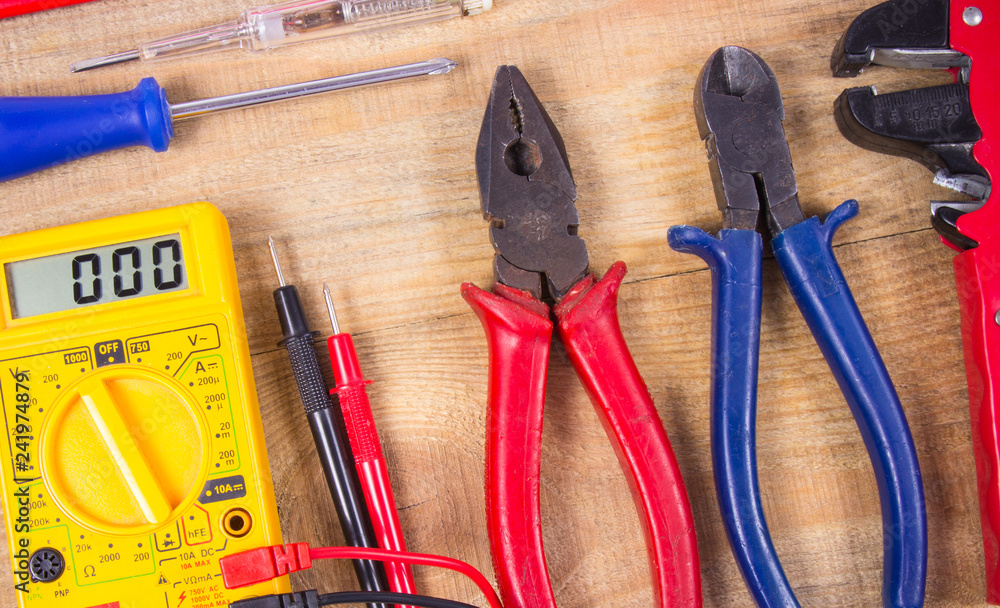 Electrical tester and other tools of electrician on a wooden background. Electrical tester and other tools of electrician on a wooden background.