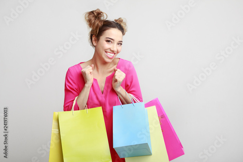 Excited lady holding shopping bagson grey background