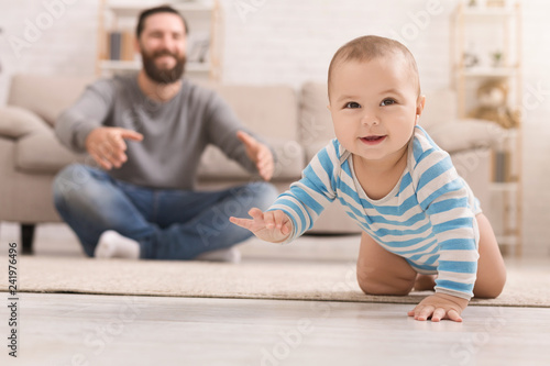 Tableau sur toile Adorable baby boy crawling on floor with dad