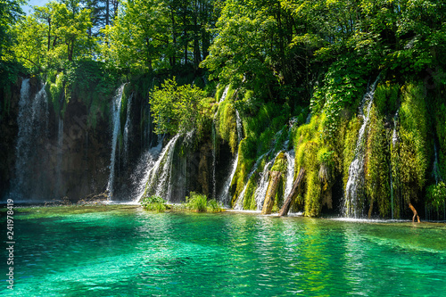 Die Plitvicer Seen sind der älteste und größte Nationalpark in Kroatien. Im Bildmittelpunkt sind Wasserfälle im Vordergrund ein See im Hintergrund sind Bäume