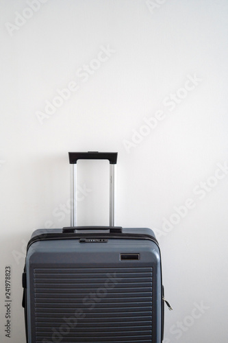 gray plastic hard suitcase with retractable telescopic handle. One suitcase prepared for a business trip. Traveling alone concept.