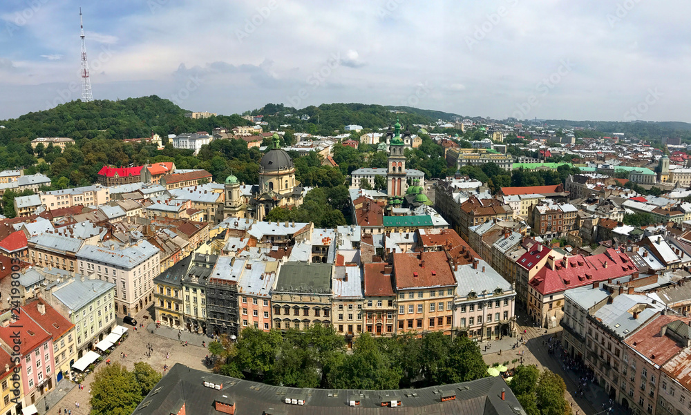 A bird's-eye view of the Ukrainian city of Lviv from the tower of the town hall where you can see the roofs of many houses around and a beautiful landscape