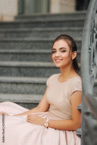 Fashion model sits on the stairs by the hotel. Beautiful lady with modern hairstyle © Aleksandr