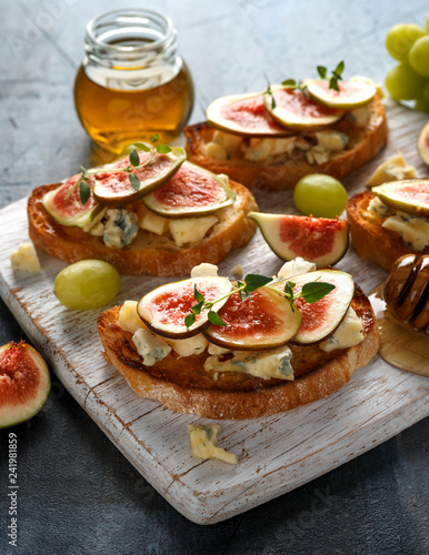 This Fig and Gorgonzola tartines, toast, bruschetta. drizzled with honey on white wooden board