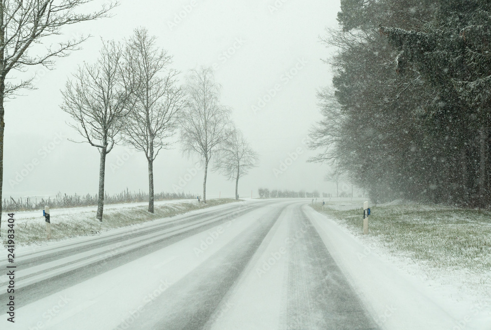 snow storm on a country road and dangerous road conditions in winter