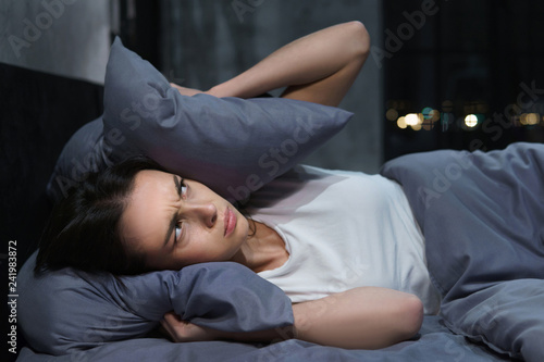Photo of annoyed young woman unable to fall asleep because of loud neighbors