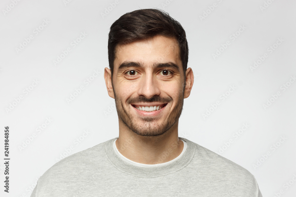 Fototapeta premium Closeup headshot of young smiling European Caucasian male isolated on gray background