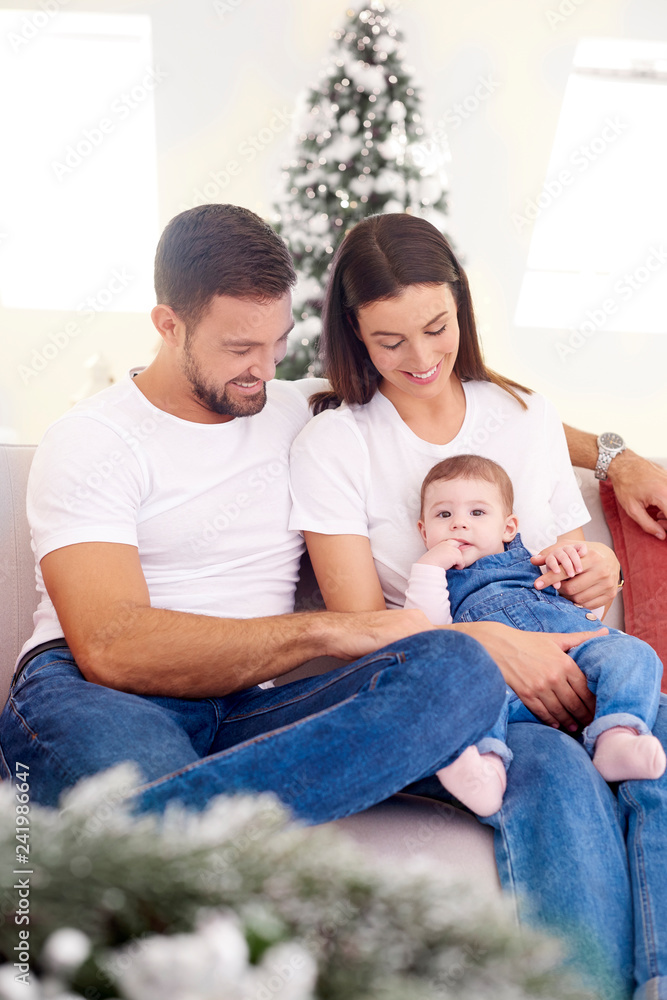 Lovely family with their baby girls relaxing on sofa at home Lovely family with their baby girls relaxing on sofa at home