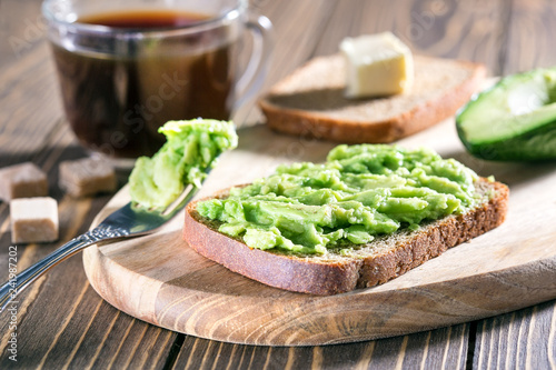 Healthy toasts with avocado and cup of black coffee on wooden table. Healthy food for breakfast.