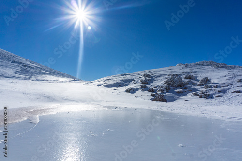 Winter landscape with a frozen lake on a sunny day near mountain Velouchi in Evritania, Greece  photo