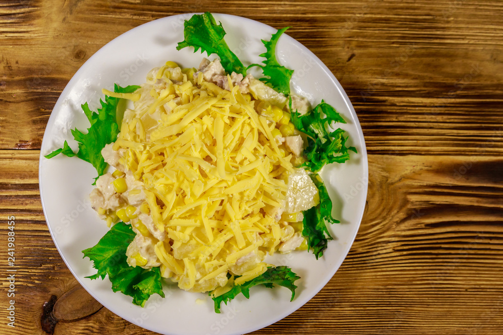 Festive salad with chicken breast, sweet corn, canned pineapple, cheese and mayonnaise on wooden table