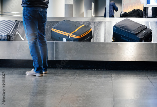 Rear view of a man preparing to take luggage from the conveyor belt in modern Airport