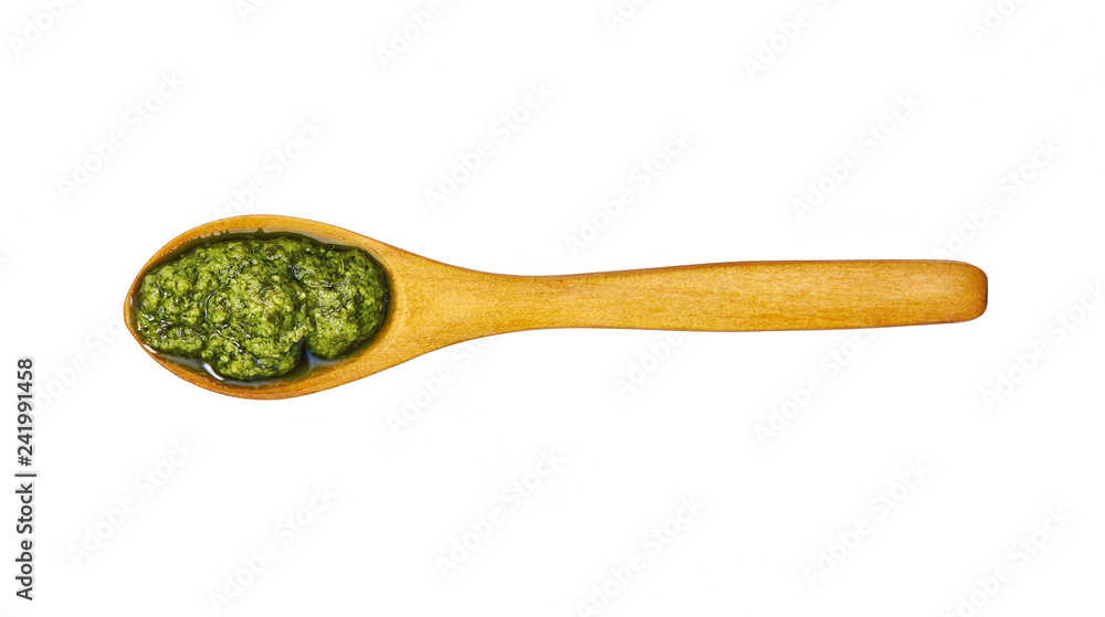 Pesto sauce in small wooden spoon isolated on white background,top view Pesto sauce in small wooden spoon isolated on white background,top view