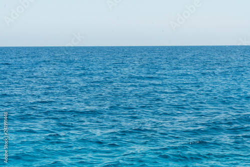 Blue sea background. Beautiful sky and blue ocean or sea. Blue sea surface with waves.