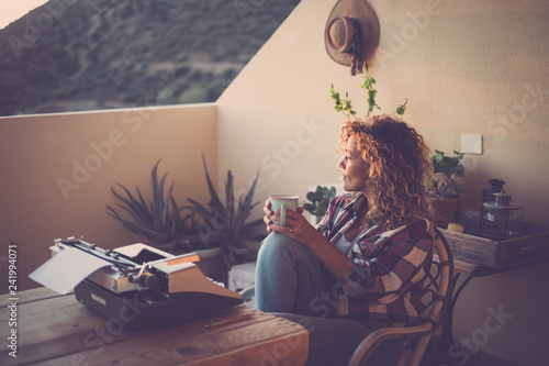 Evening lovely light and beautiful lonelyh woman taking and drinking a tea with old typewriter no technology in front on the table - alernative lifestyle and office for work and enjoy independent life photo