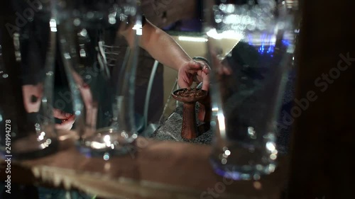 Wallpaper Mural Close-up view of preparing a Shisha in the hookah bar, the man puts tobacco in the hookah. In the foreground are blurred beer glasses. Modern cafe with hookah. Slow motion. Torontodigital.ca