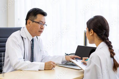 Two doctors in the hospital discuss the diagnos of the patient