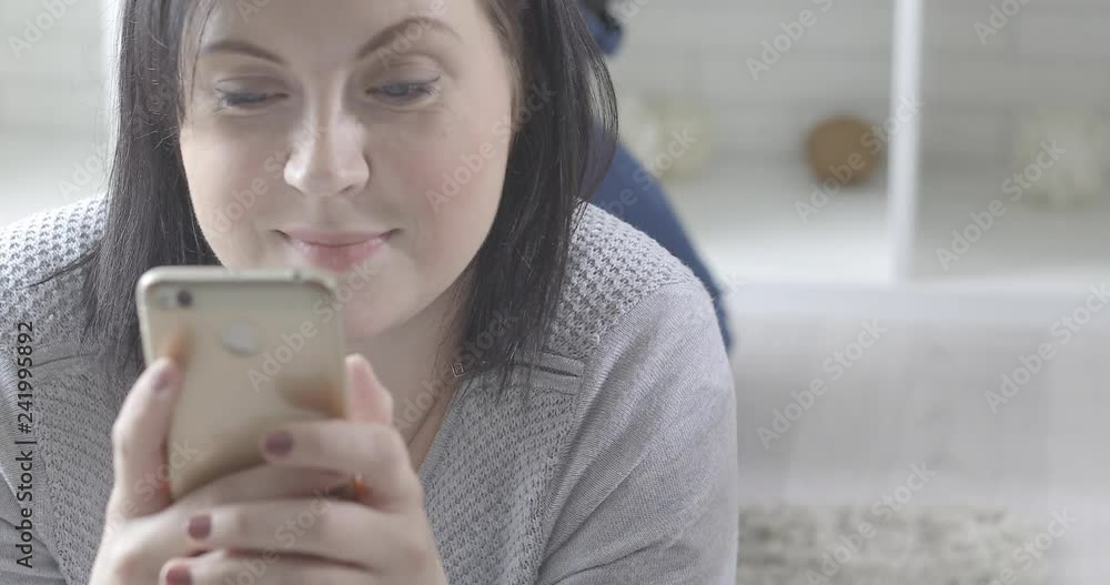 Young happy woman is browsing internet on the phone at home Young happy woman is browsing internet on the phone at home