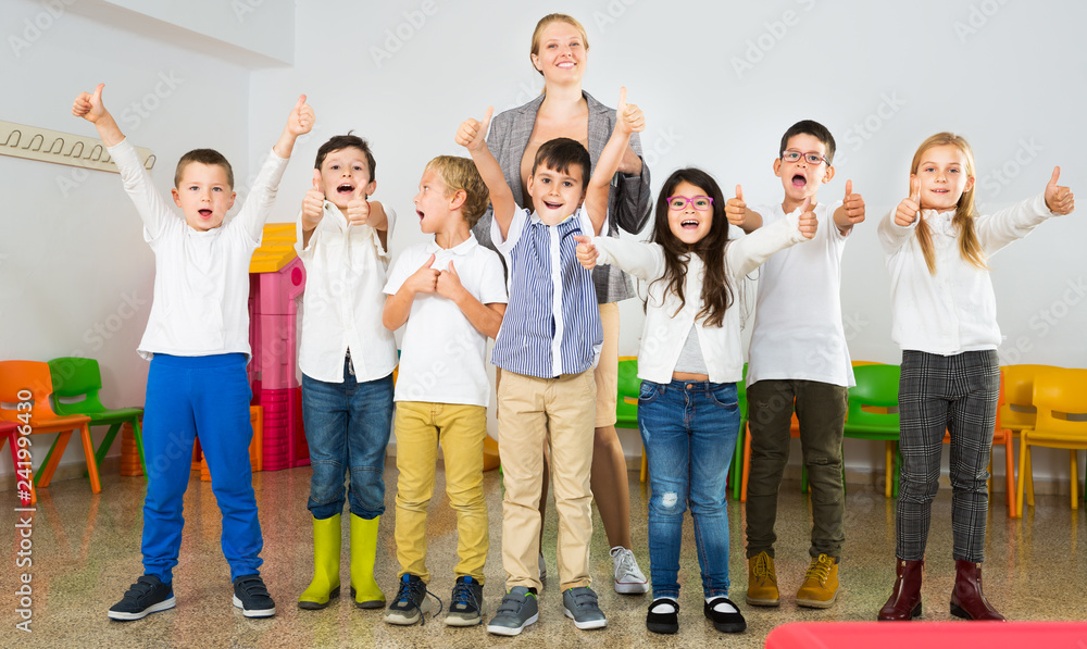 Fototapeta premium Pupils with teacher posing, giving thumbs up