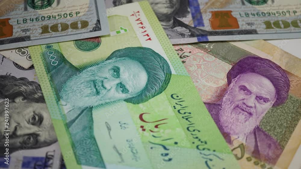 Iranian rial and dollars on rotating table. Portrait of Khomeini on