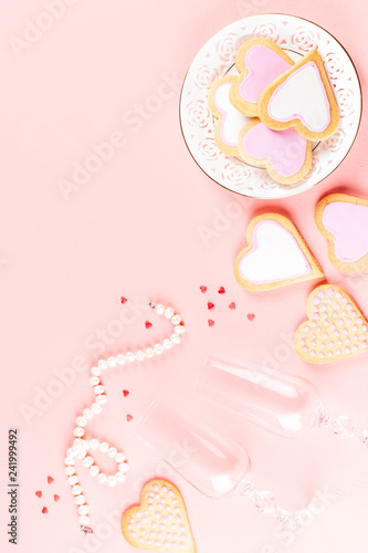 Happy Valentine's day greeting card with heart cookies, wine glasses and wine on pastel pink background.