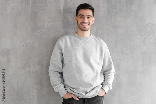 Young man in oversized sweatshirt isolated on textured gray wall background photo