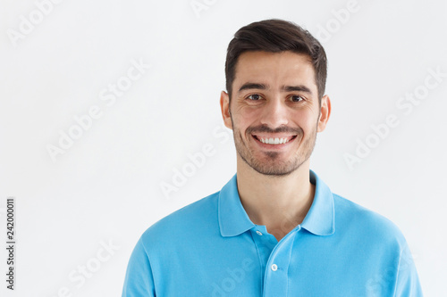 Portrait of smiling handsome man in blue polo shirt, isolated on grey background