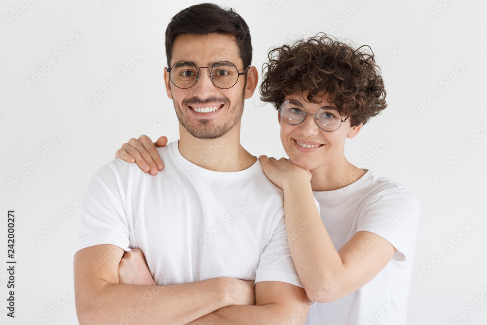 Happy young couple embracing and looking at camera, isolated on gray background Happy young couple embracing and looking at camera, isolated on gray background