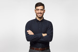 Young successful  modern business man standing with crossed arms isolated on gray background