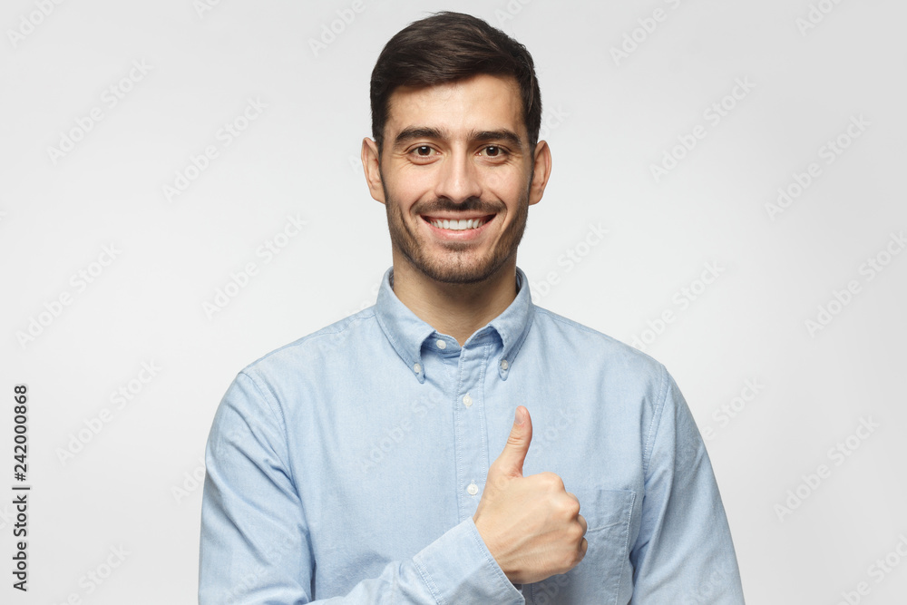 Portait of smiling businessman with thumbs up gesture, isolated on gray background
