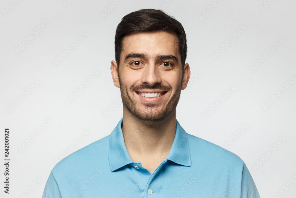 Close up portrait of young smiling handsome man in blue polo shirt isolated on gray background Close up portrait of young smiling handsome man in blue polo shirt isolated on gray background