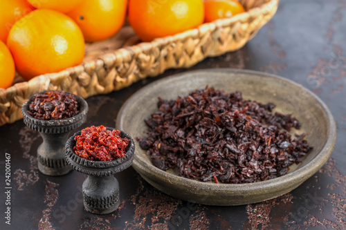 Fototapeta Naklejka Na Ścianę i Meble -  Two black burnt ceramic bowls for hookah Smoking are filled with different types of hookah on the background of ripe oranges and tangerines