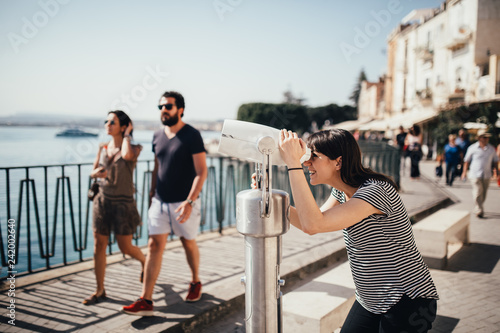 Female tourist visiting Italy.Woman in Syracuse,Sicily.Old town of Syracuse, Ortigia island visitor.Travel destination sightseeing with tourist binoculars.