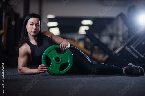 fitness girl resting in the gym, holding a shell for training. © Vladimir