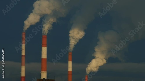 Industrial zone with a large red and white pipe thick white smoke is poured from the factory pipe in contrast to the sun. Pollution of the environment: a pipe with smoke
