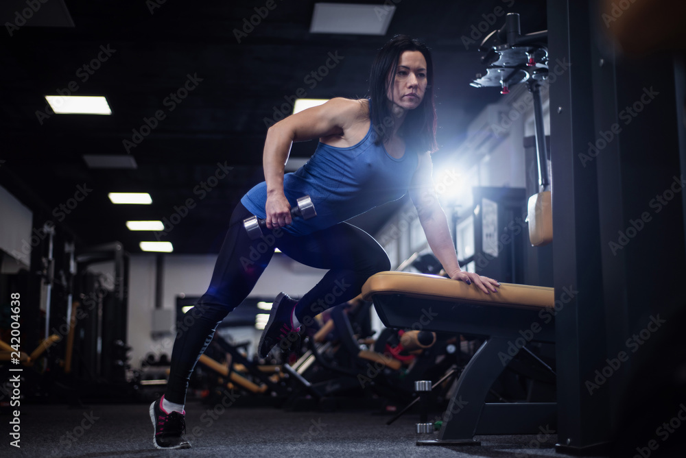 fitness girl trains back muscles and biceps with dumbbells in the gym fitness girl trains back muscles and biceps with dumbbells in the gym