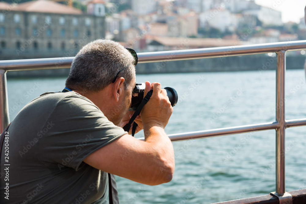 Obraz premium A man from a boat taking pictures of the cityscape of Porto. Selective focus.