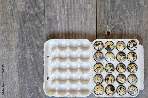 Fototapeta Naklejka Na Ścianę i Meble -  Quail eggs in a paper cast container in the form of a tray on a wooden vintage background. The concept of diet.
