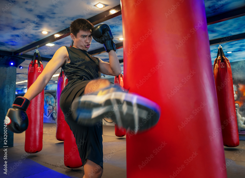 Man boxer hitting a huge punching bag at a boxing studio. Man boxer training hard. Thai boxer punch kick by punching bag, Black bacground 